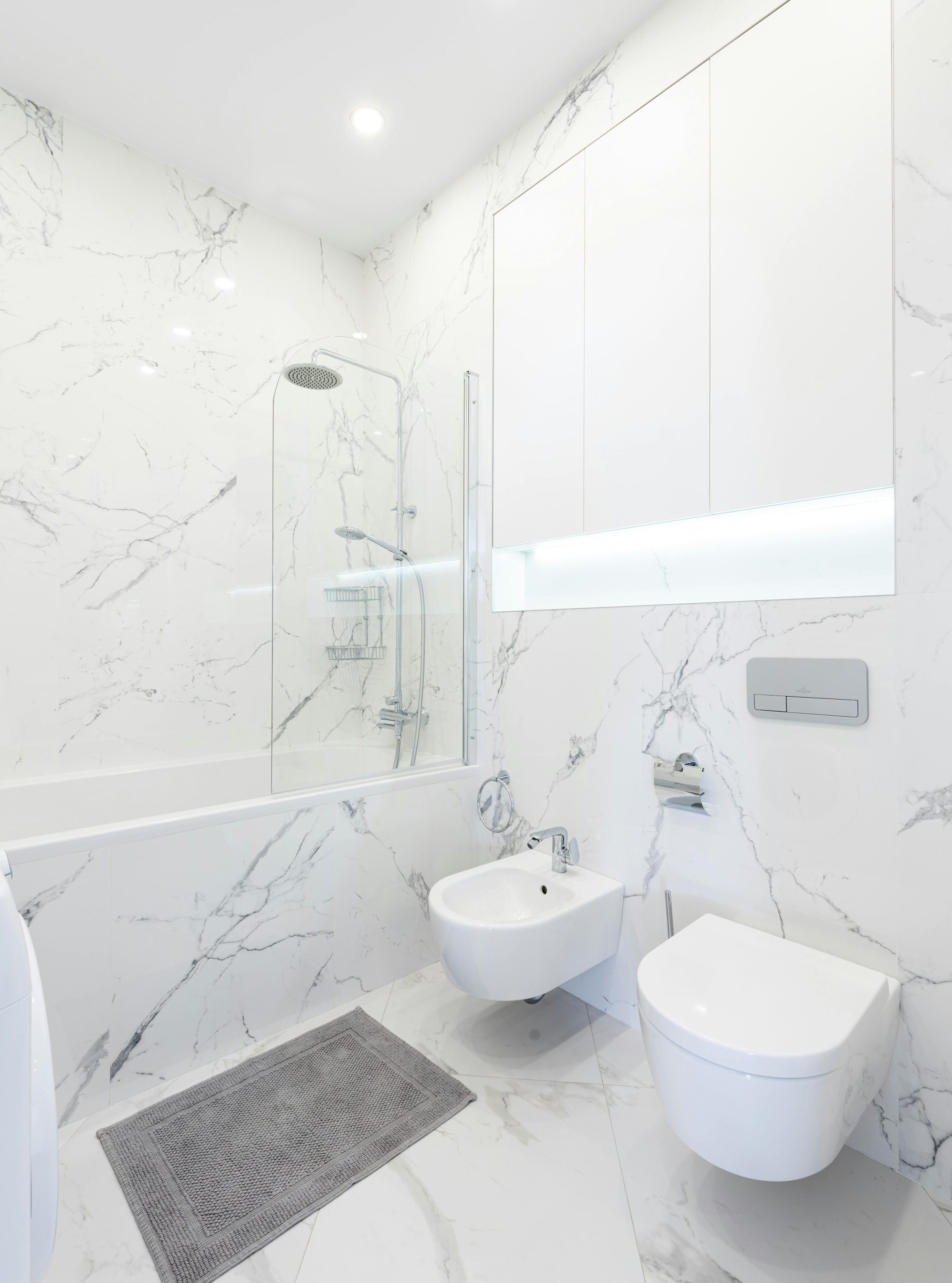 Modern white marble bathroom with bathtub, bidet, and toilet, offering a luxurious feel.